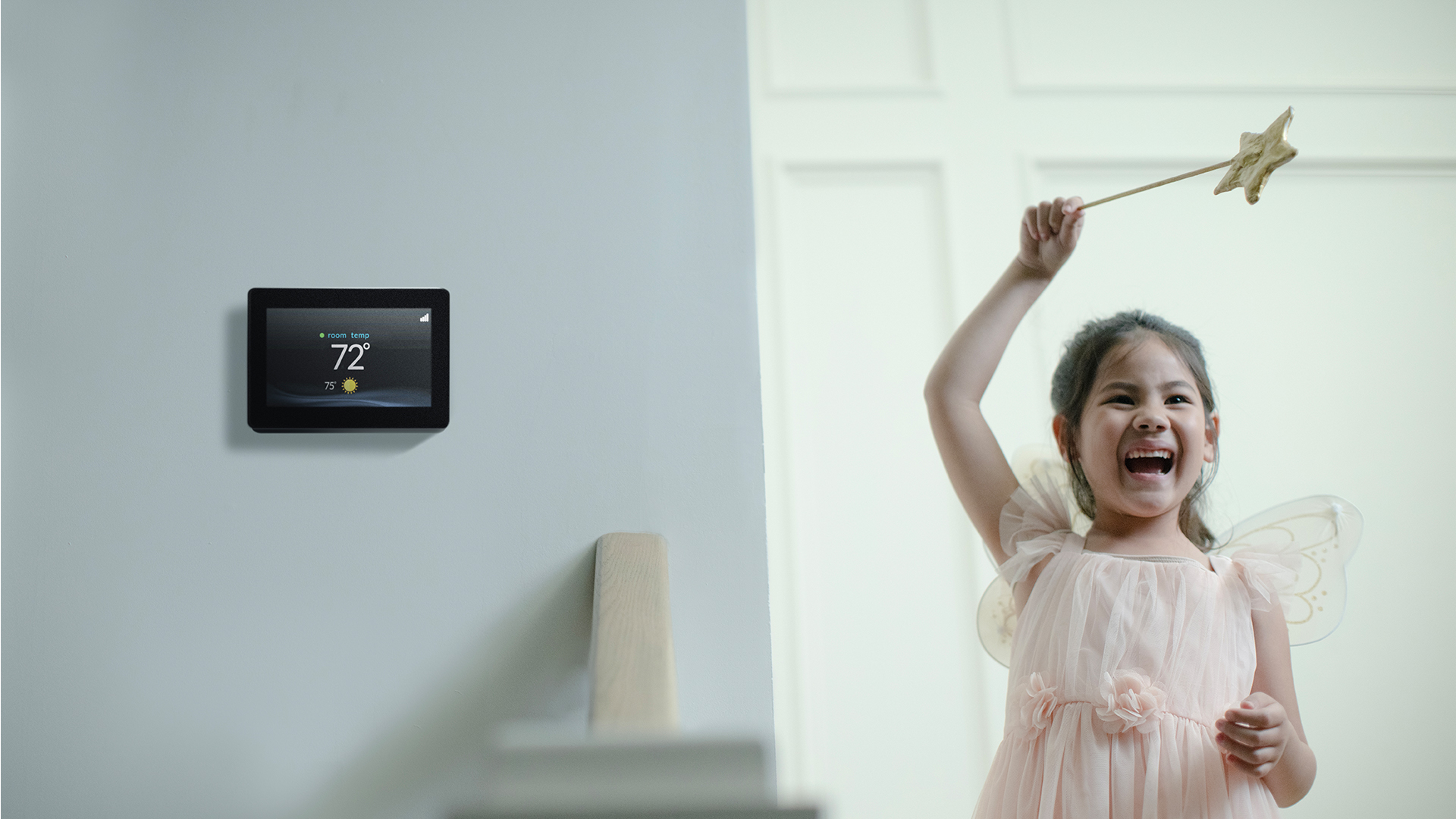 Little girl in fairy costume next to smart thermostat