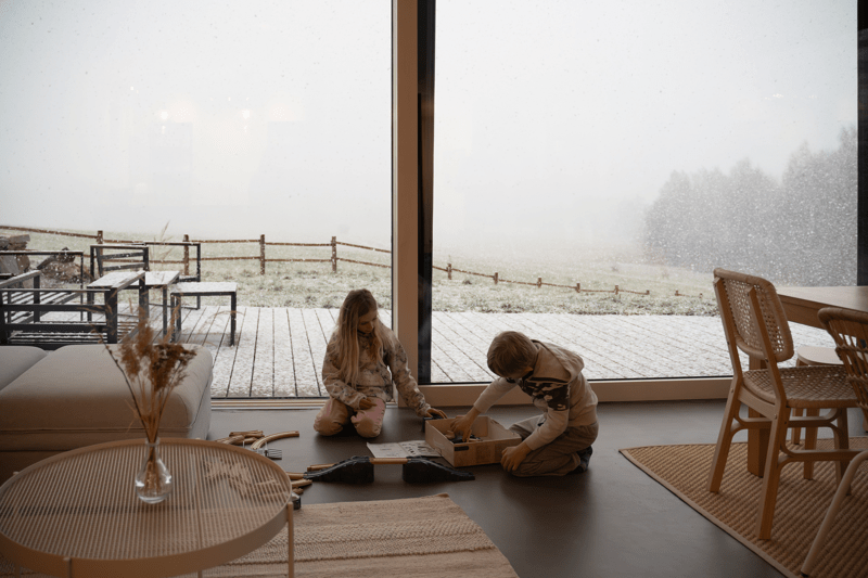 Children playing by large window at home in winter