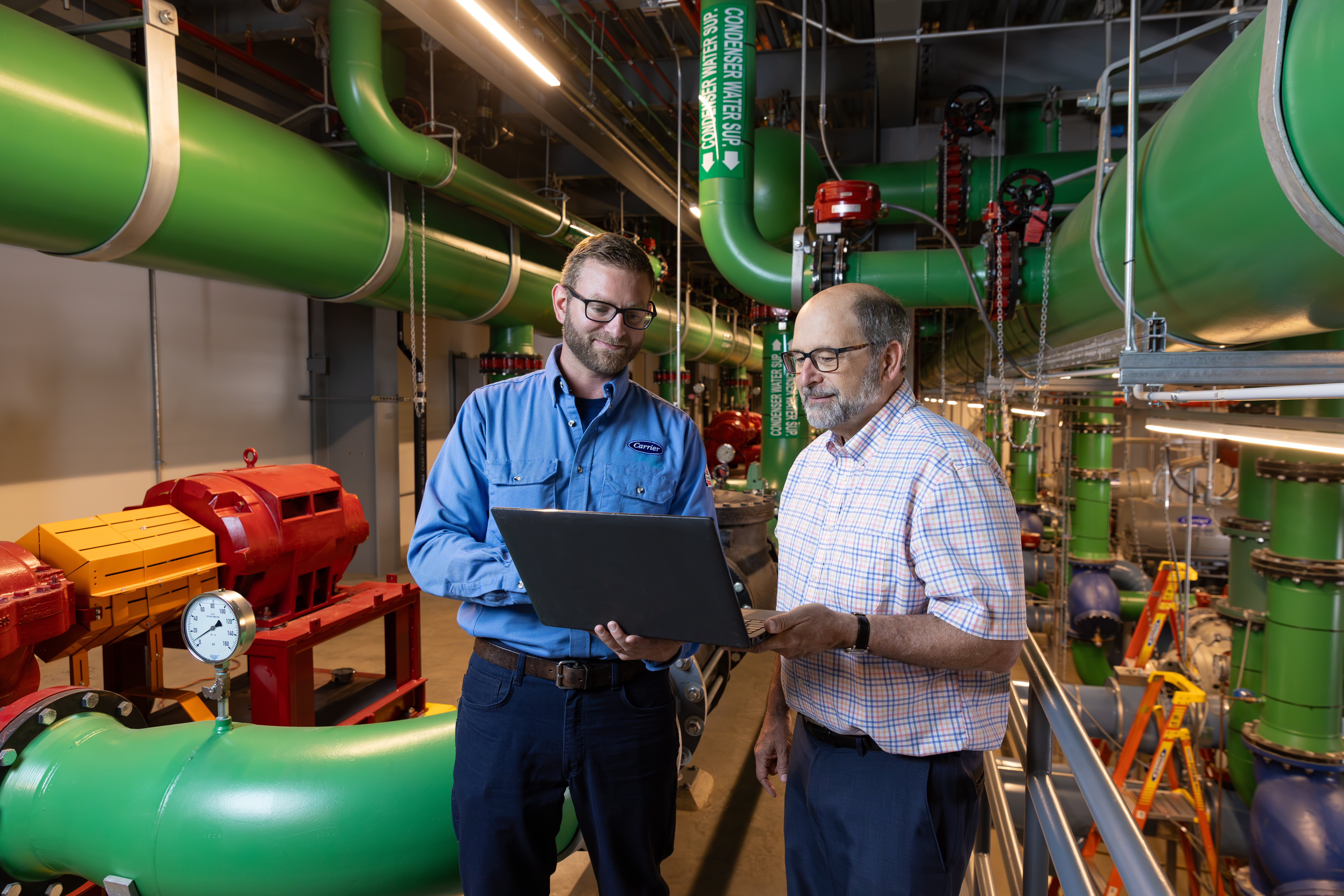 Commercial HVAC technician reviewing laptop with customer