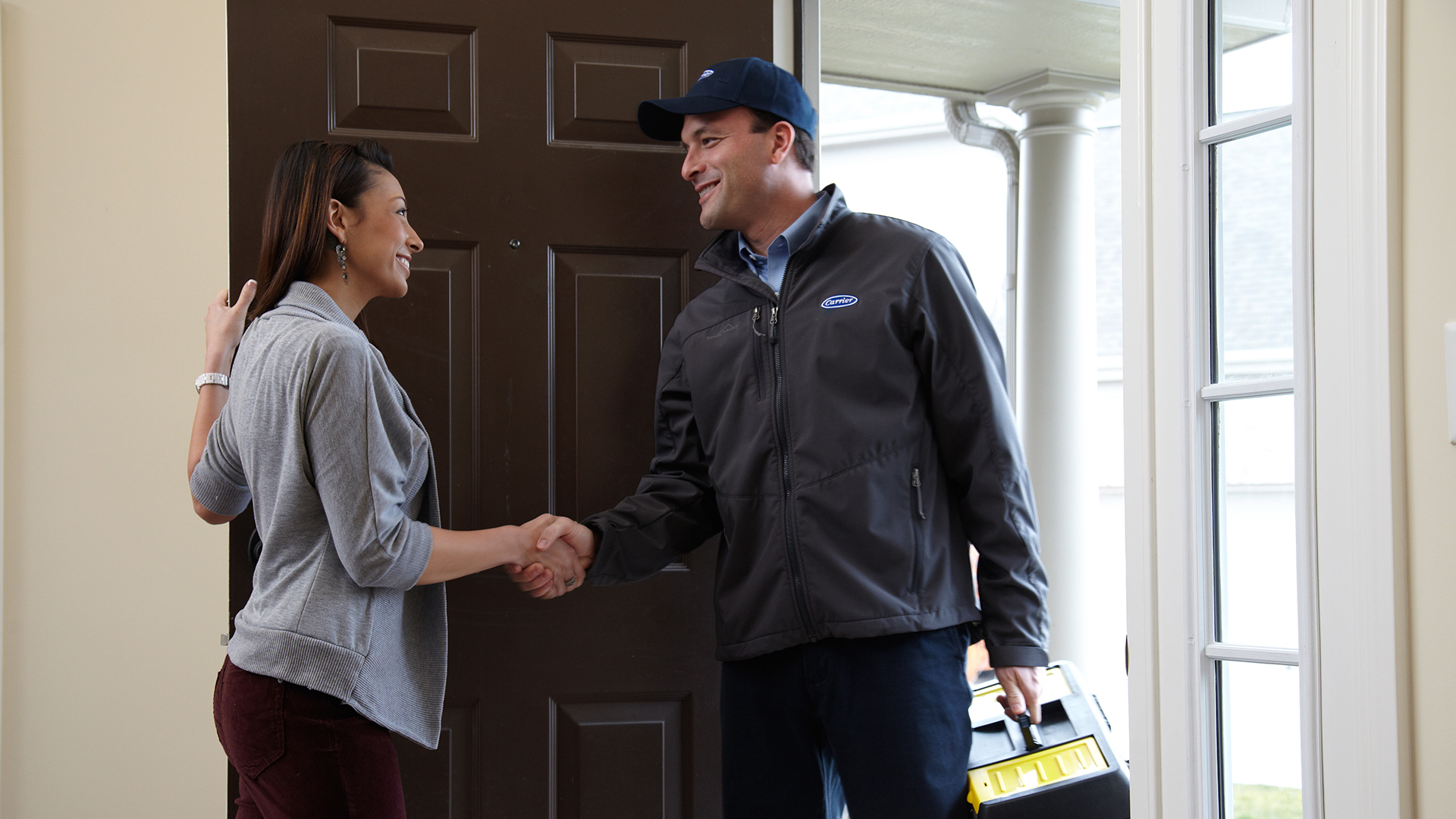 Carrier technician shaking hands with a homeowner at the front door