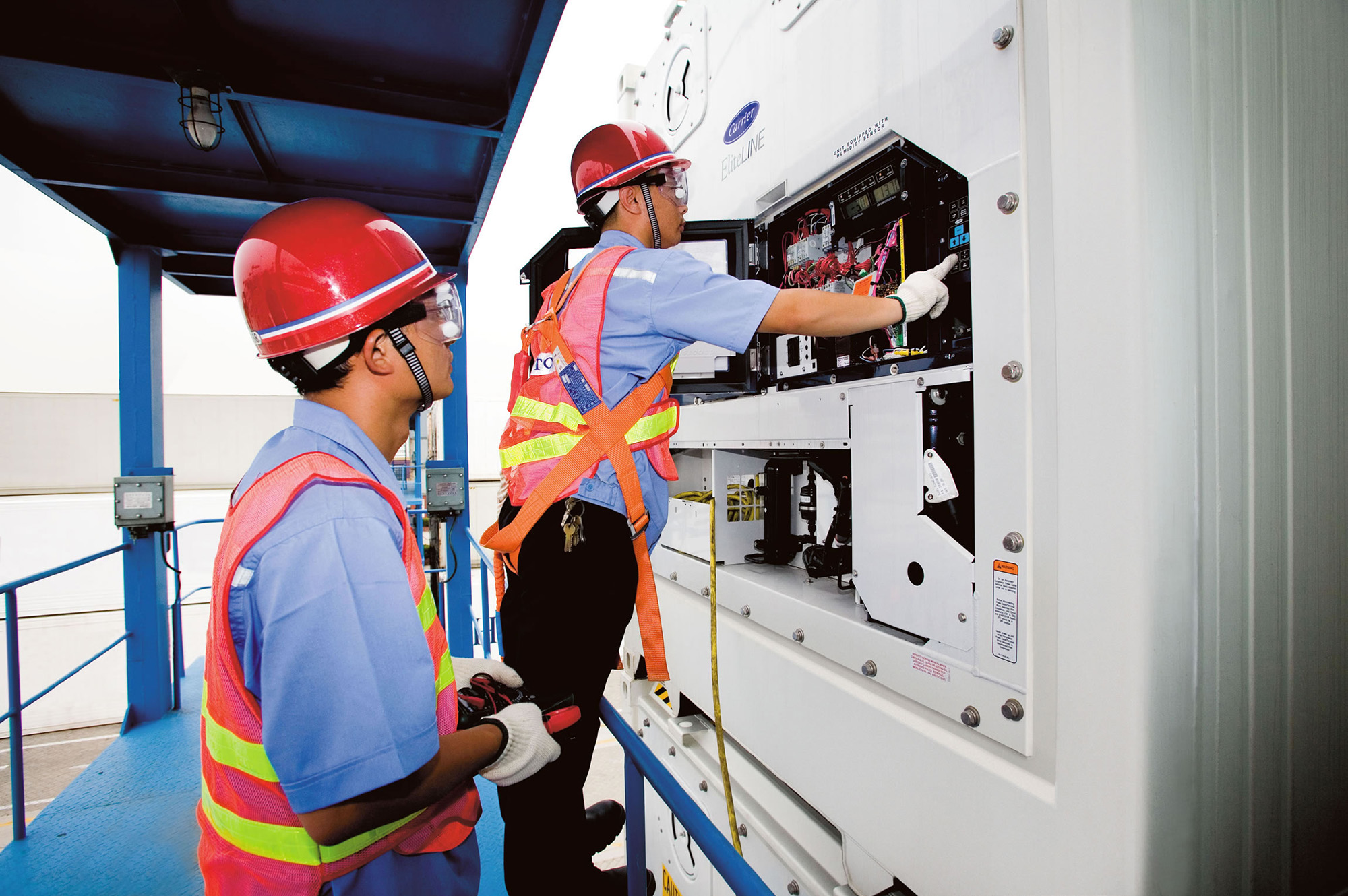 Two servicemen on container refrigeration unit
