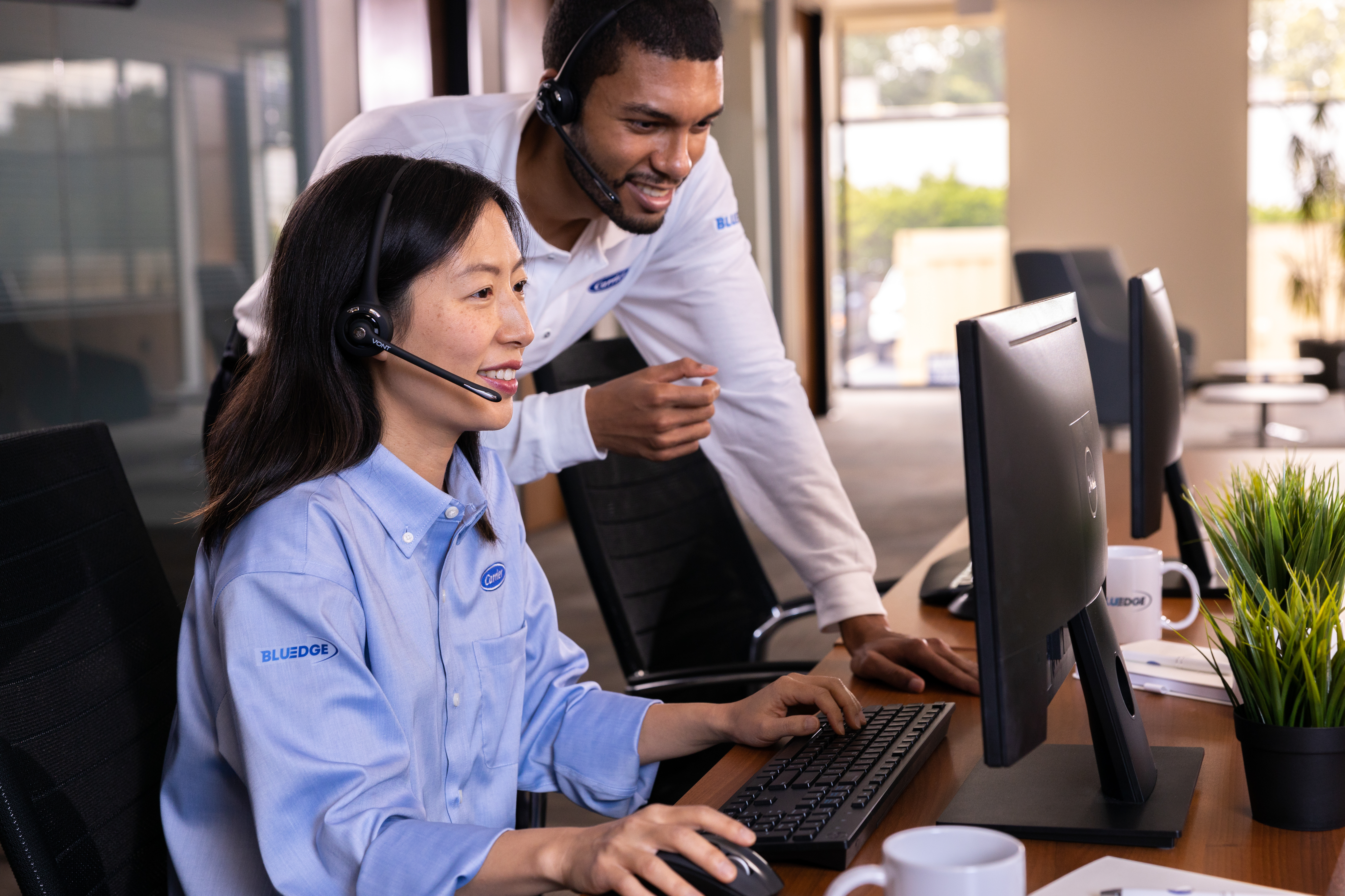 Man and woman collaborating in front of computer with headsets on