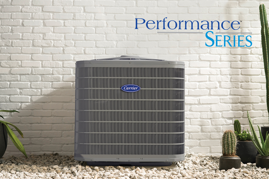 A Performance Series air conditioner installed outside a white brick home with the performance series logo nearby