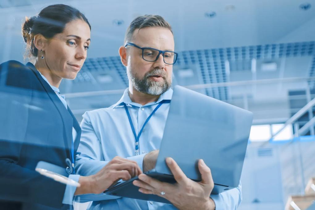 man and woman looking at laptop in office setting