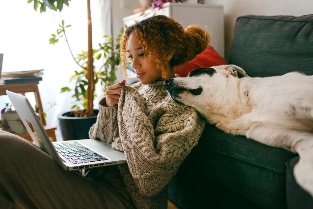  Woman sitting on floor with her laptop and dog
