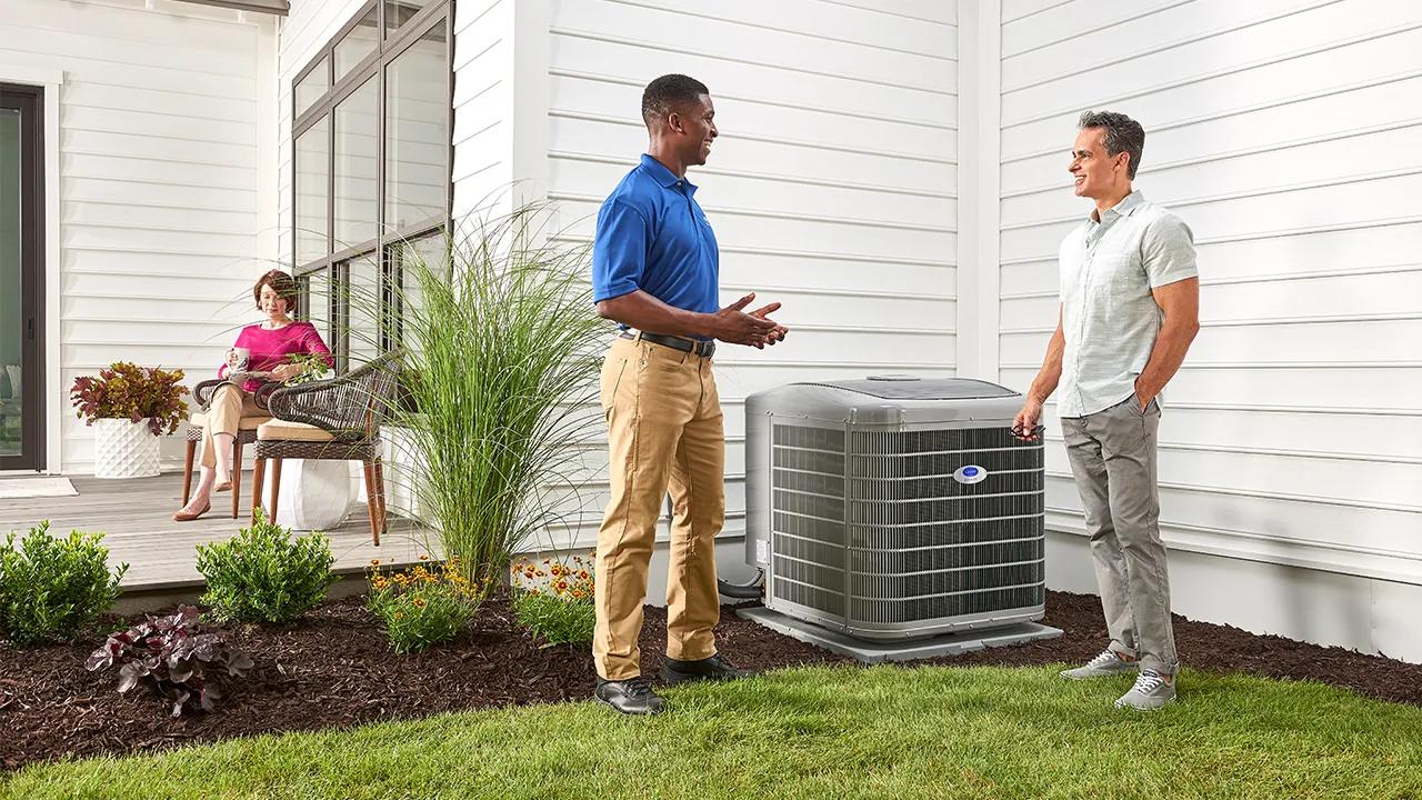 A Carrier talking to a homeowner about safety while standing next to an AC unit