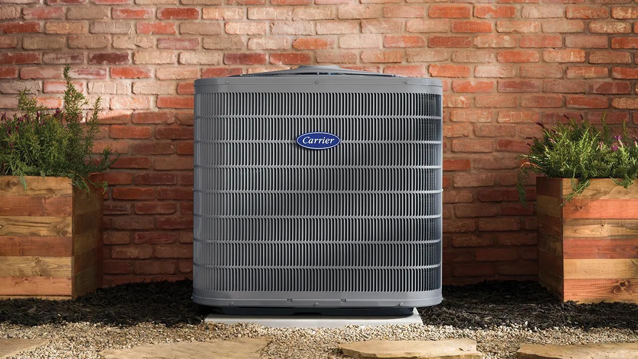 A Carrier AC unit with Puron Advance refrigerant outside a brick home