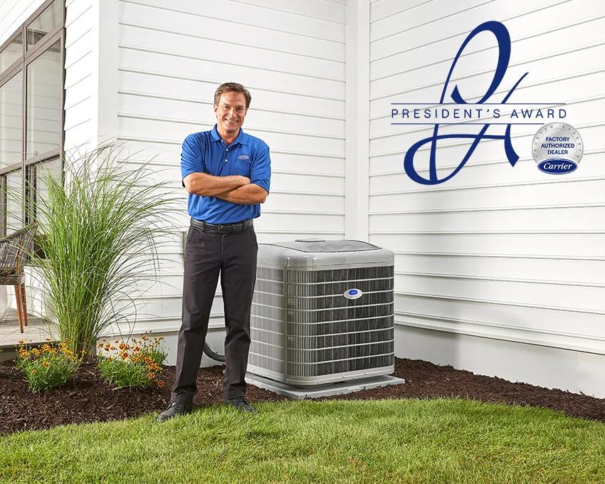 A Carrier dealer standing next to an AC unit with the President's Award logo nearby