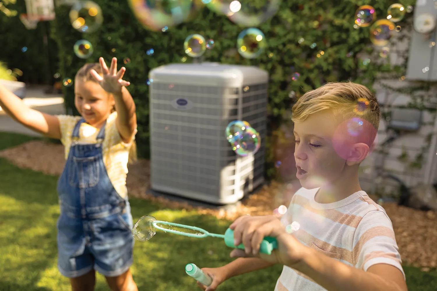 kids play with bubbles next to carrier heat pump