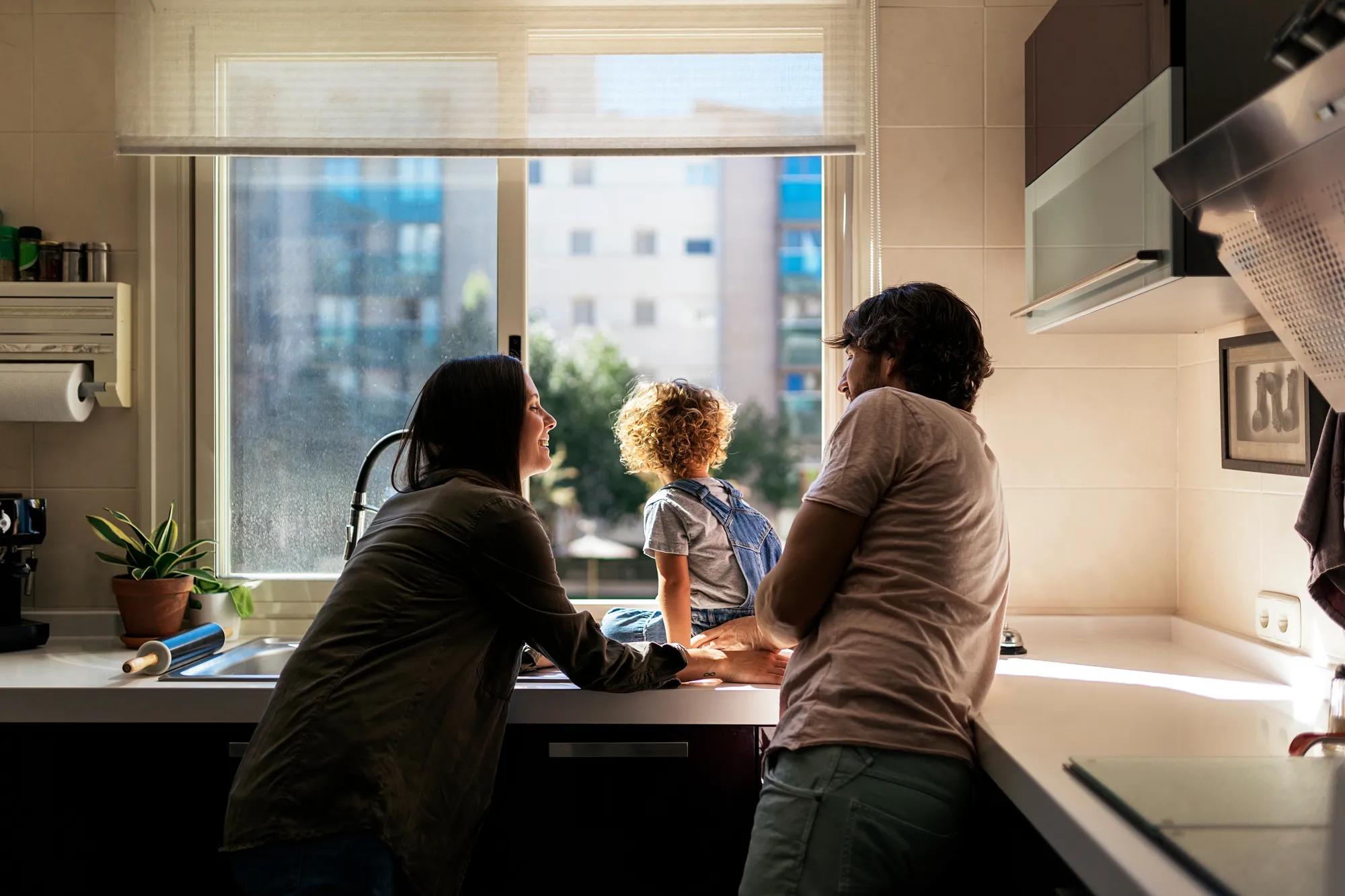 A young family looking out their kitchen window while enjoying heat from their boiler