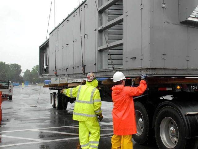 two men rigging a rooftop unit on flatbed