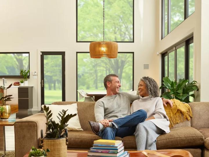 A man and woman sitting on a couch in a family room facing each other talking