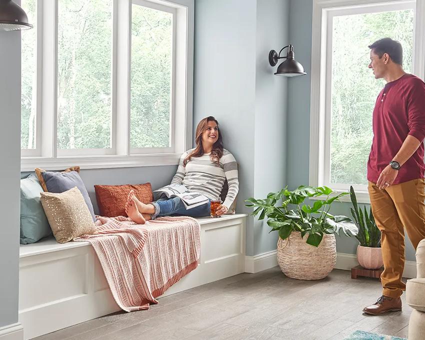 A woman sitting in a window seat speaking to her husband