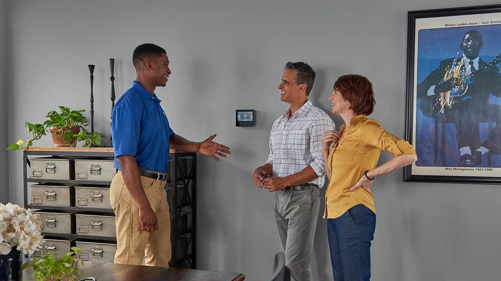 Dealer speaking with homeowners next to smart thermostat