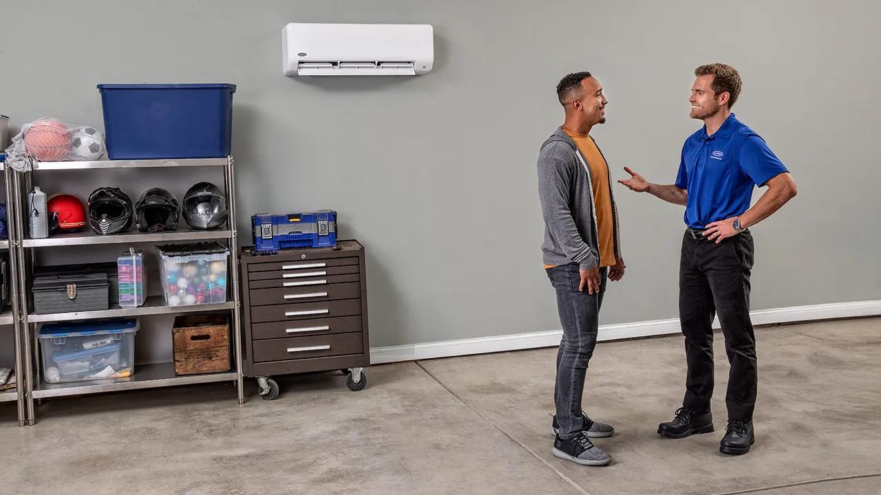 a carrier dealer and homeowner talk by ductless unit in garage