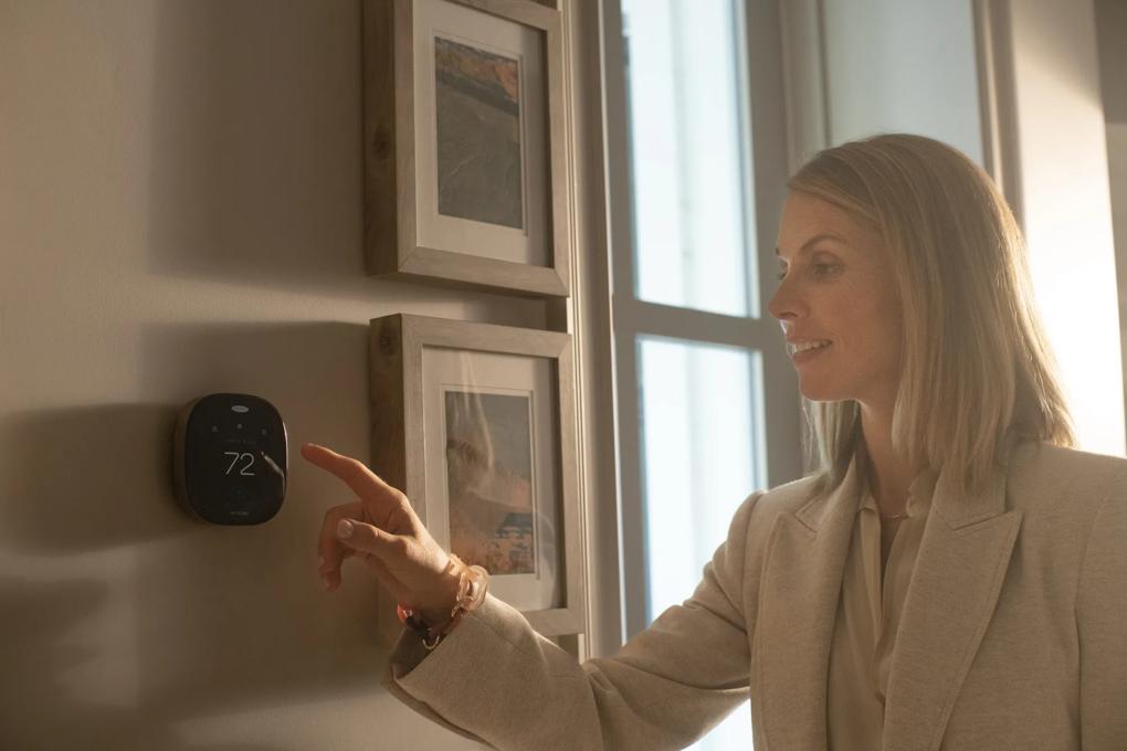 Woman changing settings on smart thermostat