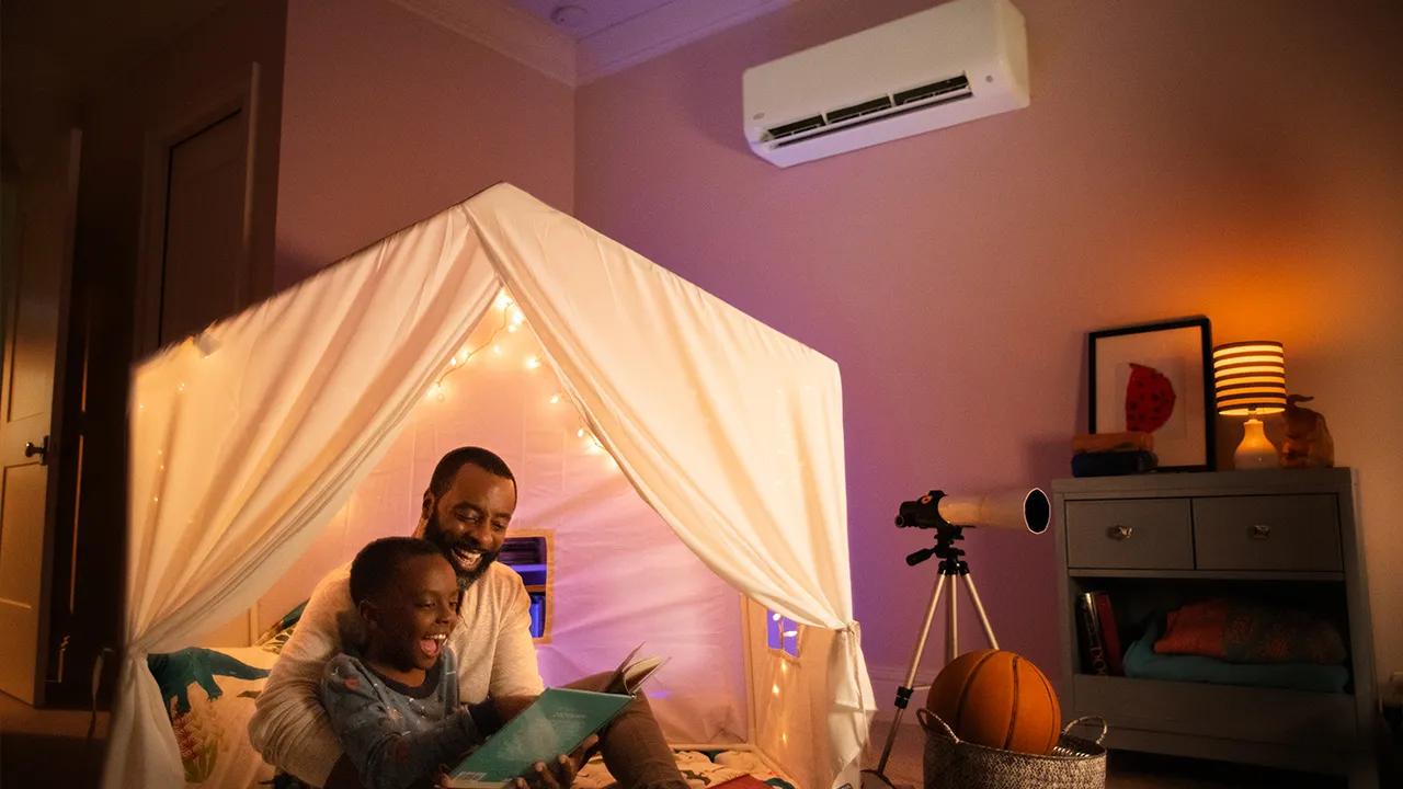 A father and son reading by homemade fort near a ductless mini split